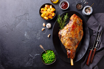 Roasted lamb leg with potato and green peas. Black background. Copy space. Top view. © annapustynnikova