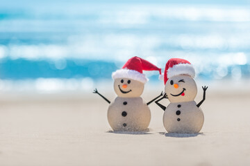 Two Sandy Christmas Snowmen are celebrating Christmas on a beautiful beach, one of them are only in focus