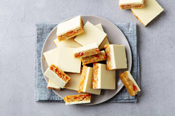 White chocolate cookies, bars with oat, coconut, apricot on a plate. Grey background. Close up. Top view.