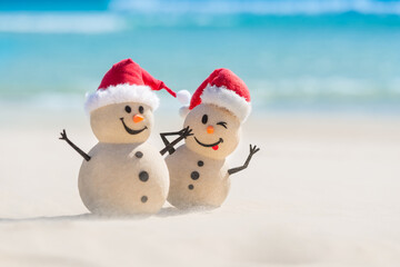 Two Sandy Christmas Snowmen are celebrating Christmas on a beautiful beach, the naughty one is in focus