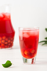Summer delicious refreshing compote of cherries with pulp and with ice in glasses on a white background, a jug with a drink