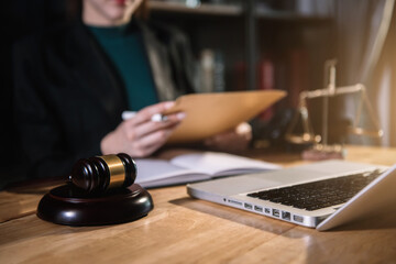 Justice and law concept. Female judge in a courtroom the gavel, working with document and digital tablet computer on wood table.