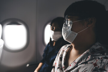 Traveller adult asian couple man and woman wear mask on airplane near window