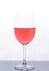 a glass with red liquid, which stands on a mirror surface, and is backlited