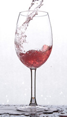 a glass with red liquid, which stands on a mirror surface, and is backlited, splashing