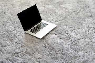 laptop and other devices on the floor on the soft carpet in living room at home, isolation during coronavirus pandemy