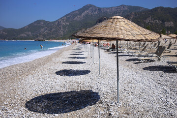 Wooden umbrellas and their shade, on the chic Oludeniz beach in Turkey.