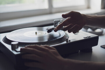 close up person's hand put the needle on a record, playing vinyl disc at the party