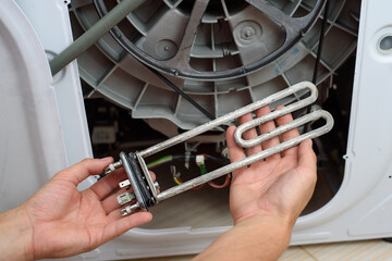 Handyman repairs the washer machine with wrench and screwdriver