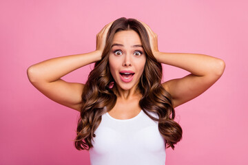 Fototapeta premium Photo of pretty funny wavy lady crazy facial expression open mouth arms on head listen cool news successful person wear white casual singlet isolated pink color background