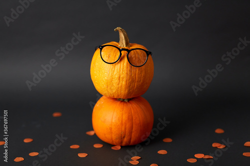 halloween and holiday concept - halloween pumpkins with glasses