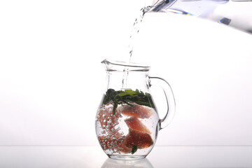 carafe of water and grapefruit on a white background