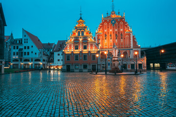 Riga, Latvia. Schwabe House And House Of The Blackheads At Town Hall Square, Ancient Historical Landmark And Popular Touristic Showplace In Summer Evening. Night Illuminations