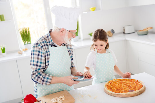 Portrait of his he her she nice friendly cheerful focused grey-haired granddad grandchild cooking delicious dish pizza cookery healthy nutrition workshop in modern light white interior kitchen house