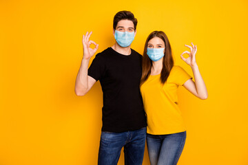 Portrait of his he her she nice attractive healthy couple showing ok-sign embracing wearing safety mask stop mers cov disease infection prevention isolated vibrant yellow color background