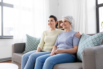 Obraz premium family, generation and people concept - happy smiling senior mother with adult daughter hugging at home