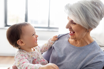 family, generation and happiness concept - happy smiling grandmother with baby granddaughter at home