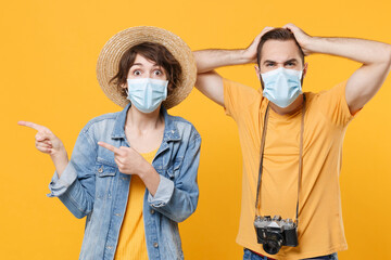 Shocked tourists couple friends guy girl in face mask isolated on yellow background. Epidemic pandemic coronavirus 2019-ncov sars covid-19 flu virus concept. Pointing fingers aside put hands on head.