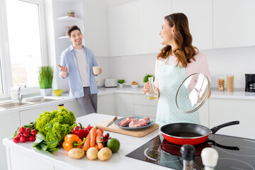 Portrait of two nice attractive cheerful cheery glad spouses making domestic fresh homemade dish cookery in light white interior kitchen house apartment indoors