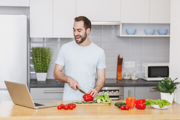 Cheerful young man guy in casual t-shirt using laptop computer making video call preparing...