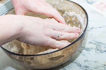 Thick dough is manually mixed in a transparent bowl.
