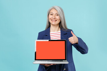 Smiling gray-haired business woman in blue suit posing isolated on blue background studio....