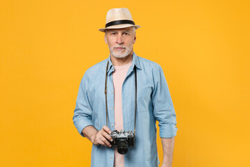 Traveler tourist elderly gray-haired man in summer clothes hat photo camera isolated on yellow wall background. Passenger traveling abroad to travel on weekends getaway. Air flight journey concept.
