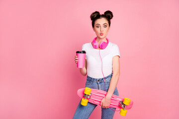 Portrait of her she nice attractive comic girlish cheerful cheery girl listening music drinking latte holding in hands skate board pout lips having fun isolated over pink pastel color background