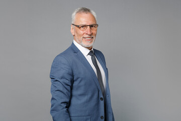 Side view of smiling elderly gray-haired mustache bearded business man in classic blue suit shirt tie isolated on grey background studio. Achievement career wealth business concept. Looking camera.