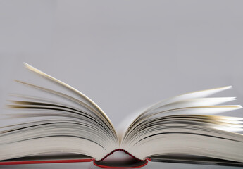 Open book with red cover and narrow depth of field on light background. Copy space above the book
