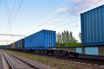 Cargo Containers Transportation On Freight Train By Railway. Intermodal Container On Train Car. Rail Freight Shipping Logistics Concept. Soft focus, possible granularity. Object in motion