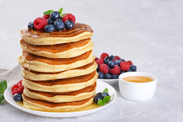 Pancakes with fresh berry and honey on gray background. Healthy breakfast.