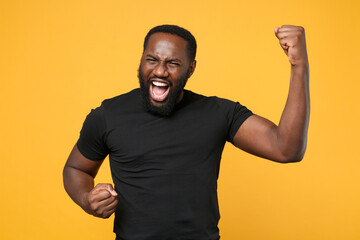 Overjoyed african american man guy football fan in casual black t-shirt isolated on yellow wall...