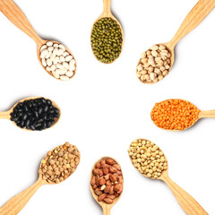 Spoons with different raw legumes on white background