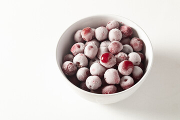 Frozen berries in a white plate on a light background