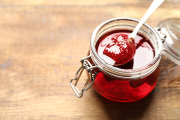 Delicious pickled strawberry jam in glass jar on wooden table, closeup. Space for text