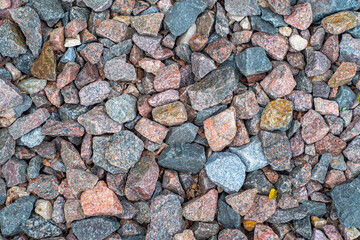 Background with gravel of cranite stones, mostly red granite. Background with stones and rare plant sprouts.