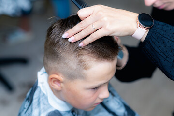 Obraz na płótnie Canvas Close up caucasian american pretty school boy trendy haircut at bright modern barbershop.