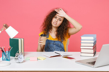 Tired african american girl employee in office isolated on pink background. Achievement business career. Education in school university college concept. Hold cup of coffee or tea, put hand on head.