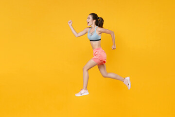 Fototapeta na wymiar Full length portrait of excited fitness woman girl in sportswear working out isolated on yellow background studio. Workout sport motivation lifestyle concept. Mock up copy space. Jumping like running.