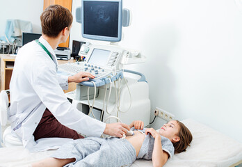 Doctor watching monitor while performing ultrasound scan on a ten year old girl
