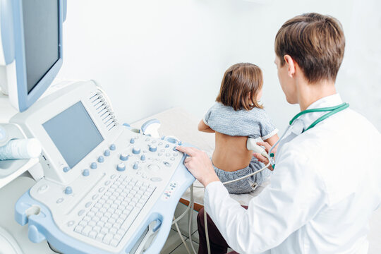 Young doctor performing kidney ultrasound scan on a ten year old girl