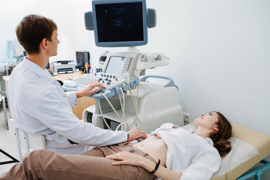 US specialist performing ultrasound scan on a young female patient.