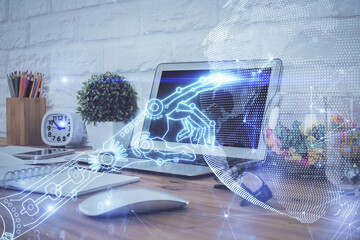 Computer on desktop in office with technology theme hologram. Double exposure. Tech concept.