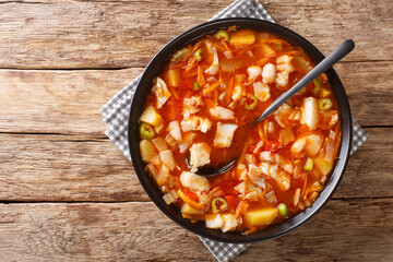 Bermuda fish tomato soup with seasonal vegetables and black rum close-up in a bowl on the table. Horizontal top view from above