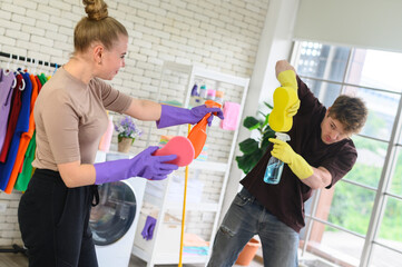 Young happy couple is having fun while doing cleaning at home.