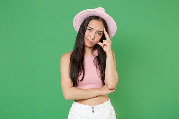 Preoccupied tired young asian woman girl in casual pink clothes hat isolated on green wall background studio portrait. People sincere emotions lifestyle concept. Mock up copy space. Put hand on head.