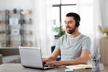 remote job, technology and people concept - happy smiling man with headset and laptop computer...