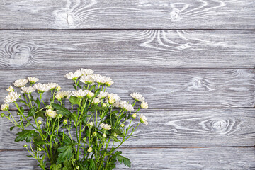 A bouquet of white bush chrysanthemums on a wooden table
