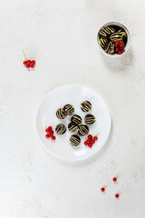 Homemade chocolates with cinnamon and cardamom, garnished with red currants. Sugar, lactose, gluten free. Vertical orientation, top view.